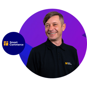 Lächelnder Mann in schwarzem Poloshirt mit Logo von Smart Commerce, präsentiert Lösungen für Online-Shops von FactFinder.